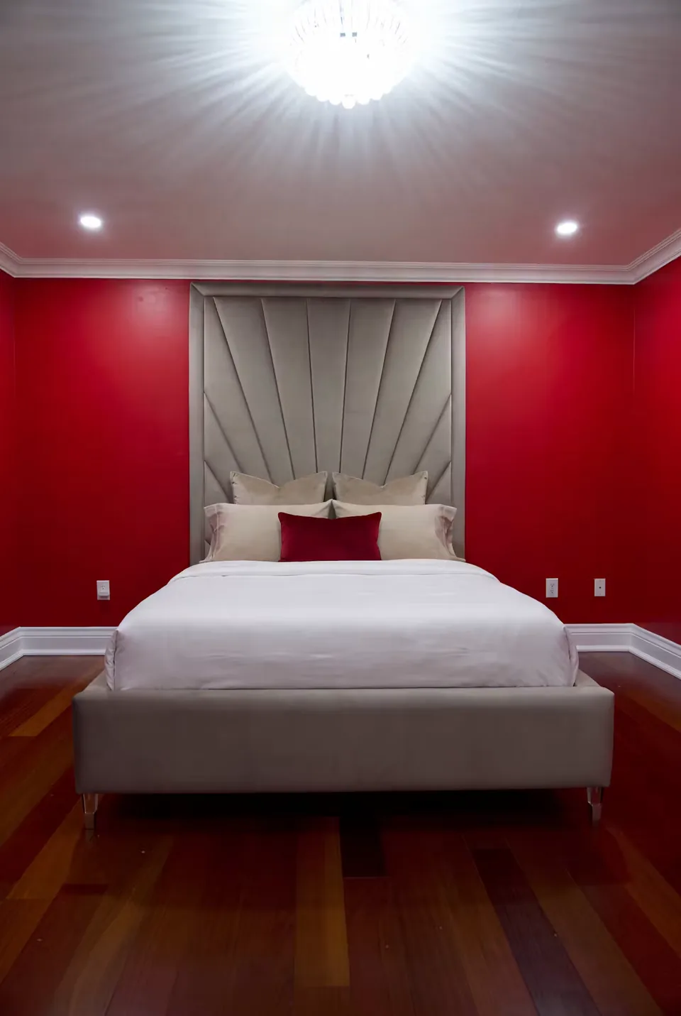 Sand upholstered bed with a fan headboard against crimson walls