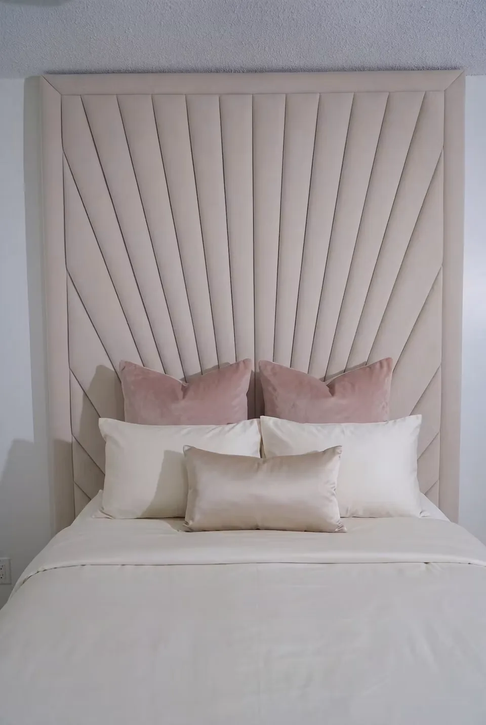 Front detail of the sand-coloured rays rising behind blush pillows