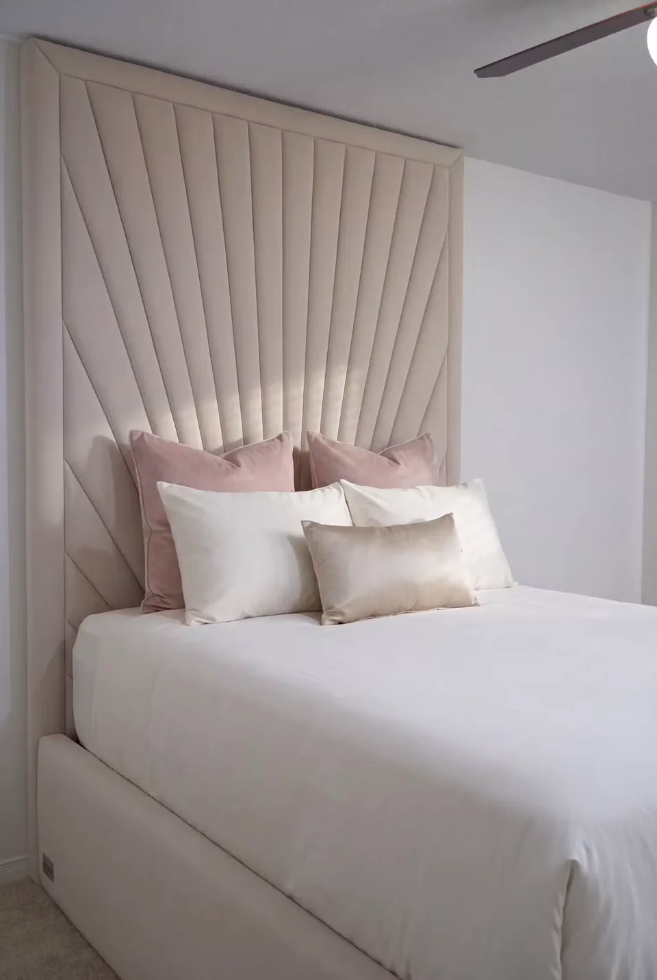 Angled view of the tall fan headboard and pale upholstered bed