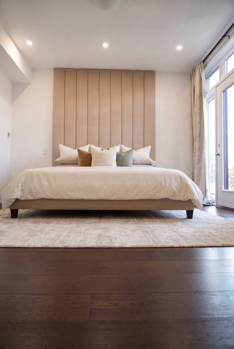 Front view of the pale bed and ceiling-height channel headboard.