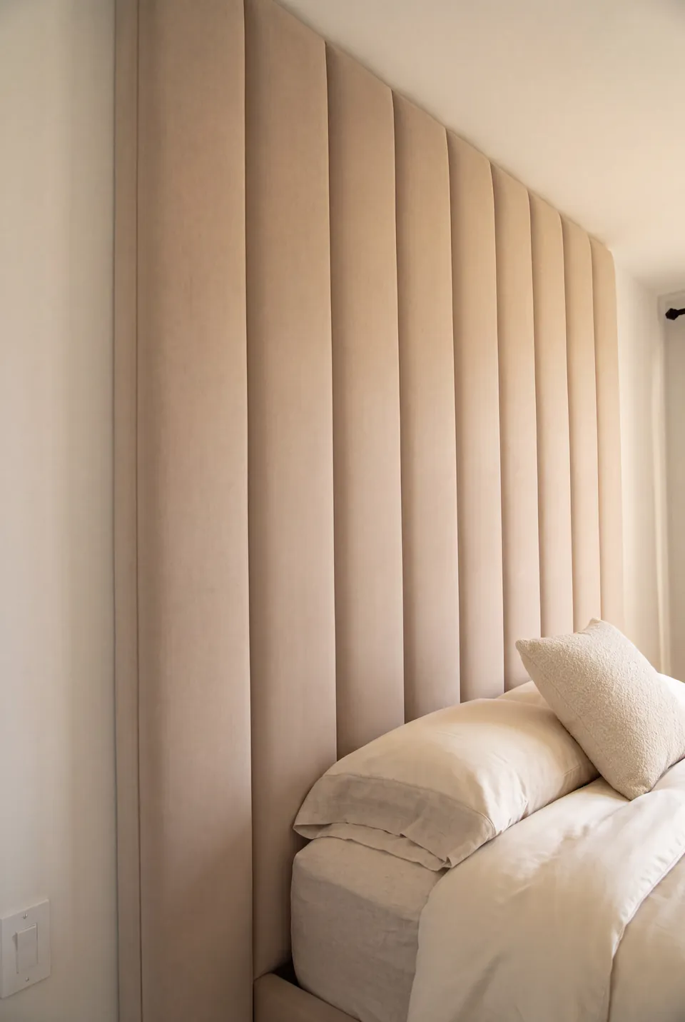 Close side view of neutral pillows against sand-coloured vertical upholstery.