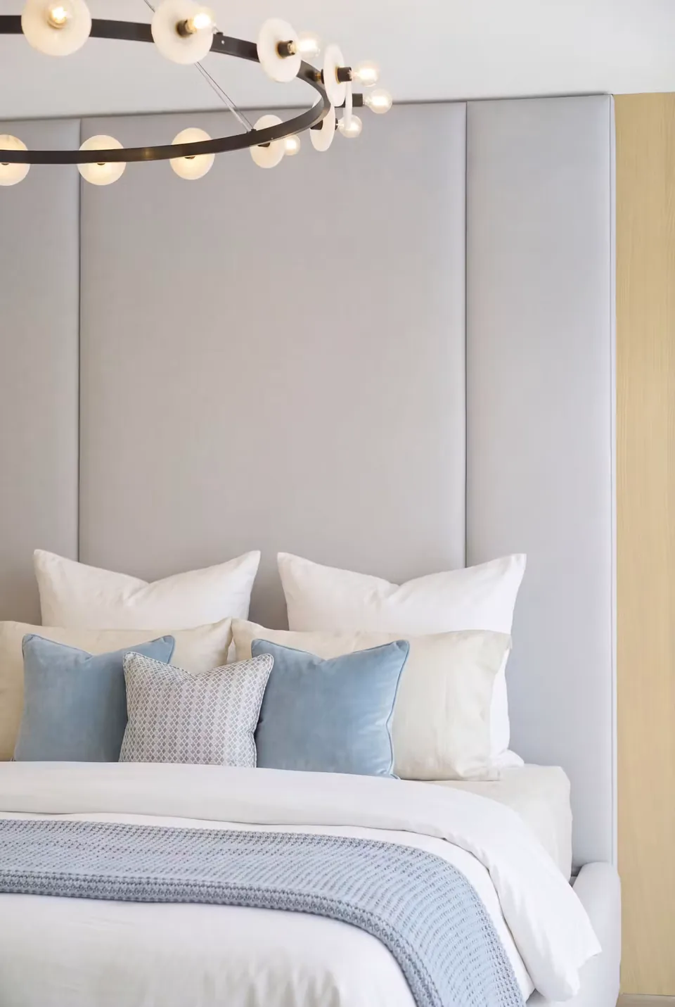 Close view of grey padded columns, fine gold divisions and white pillows beside the headboard.