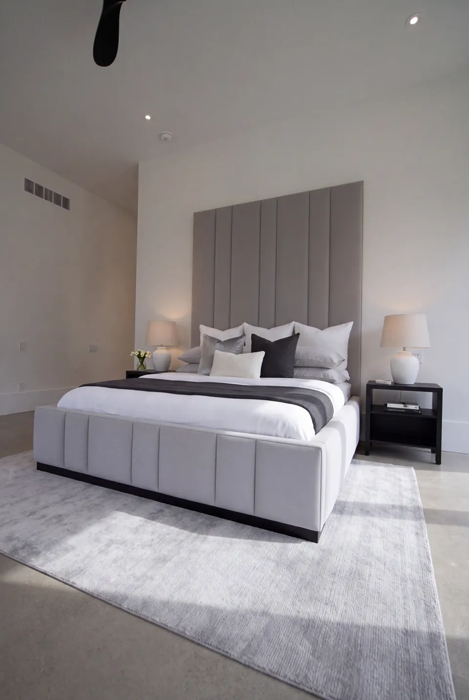 Full angled view of a silver-grey upholstered bed with channelled headboard and footboard.