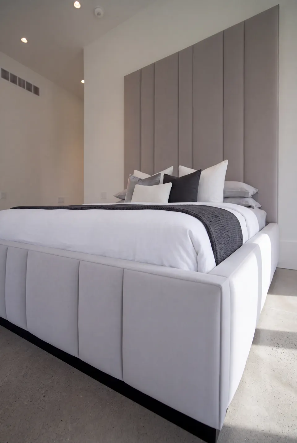 Close angled view of the divided upholstered footboard and tall grey headboard.