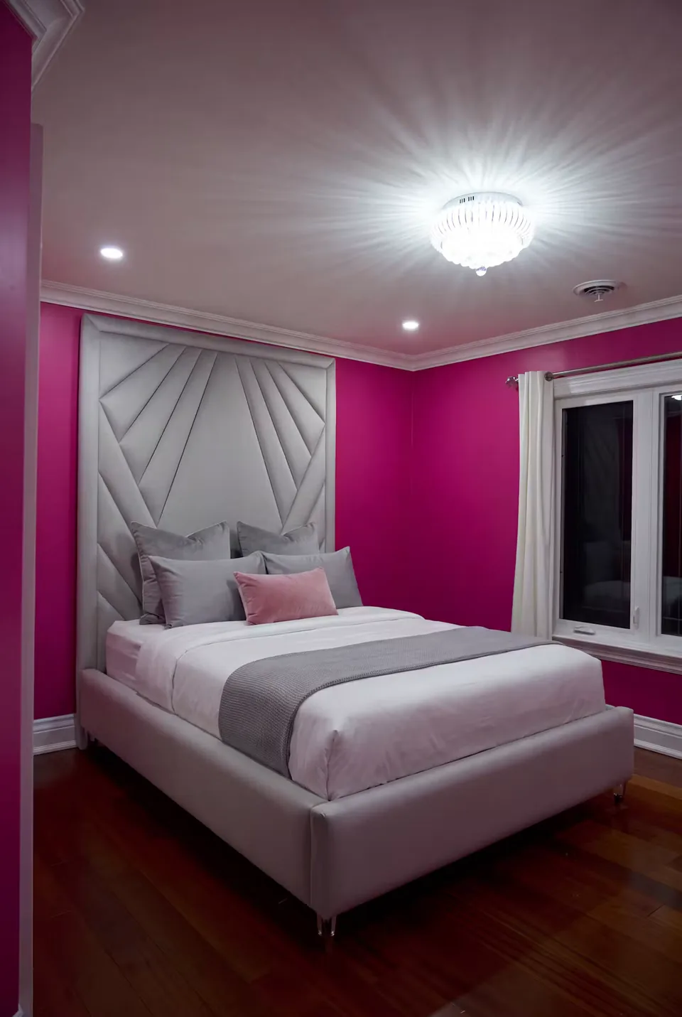Full silver-grey bed with a radiating headboard against fuchsia walls