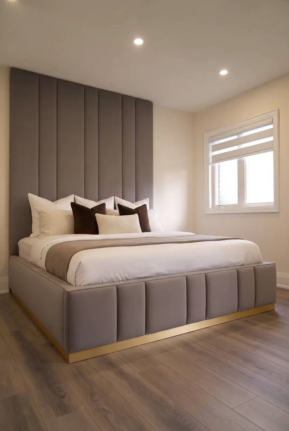 Full angled view of a slate-grey channelled bed with a padded footboard and gold base.