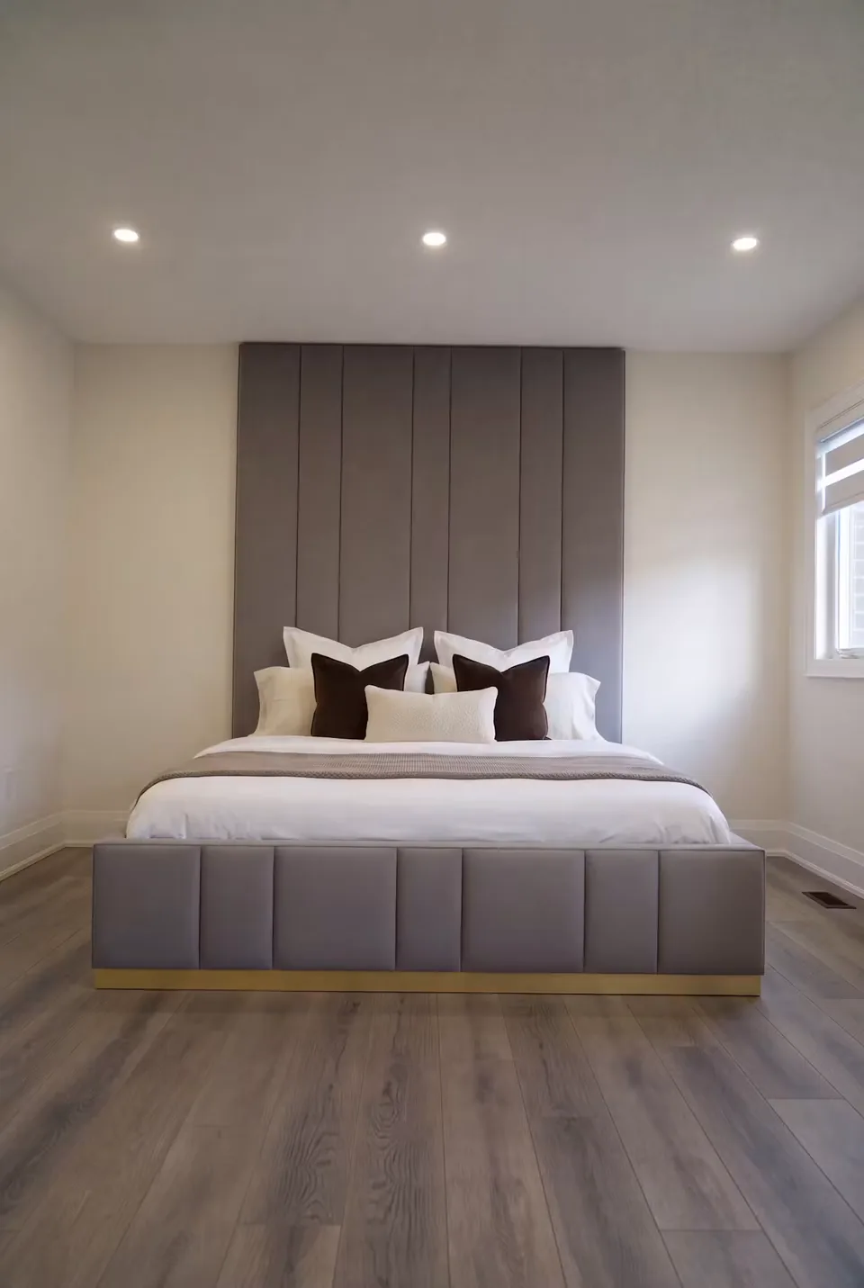 Full front view of the grey upholstered bed and tall vertically divided headboard.