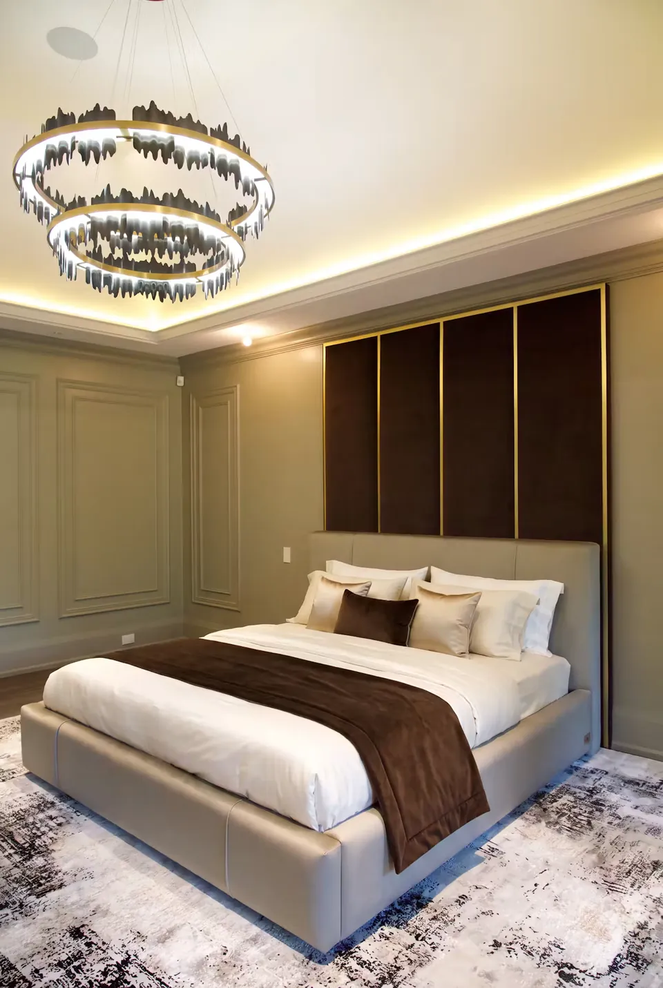 Full angled view of a slate upholstered bed beneath tall cocoa wall panels with gold divisions.