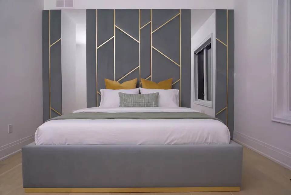 Full slate-grey bed beneath a gold branching upholstered wall