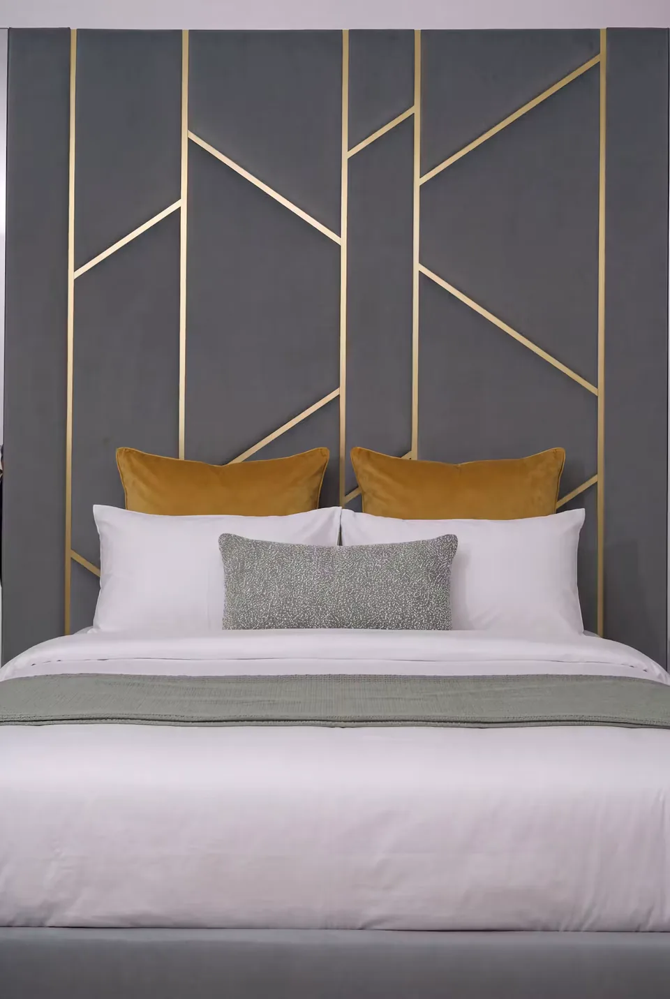 Front detail of gold branches behind white bedding and ochre pillows