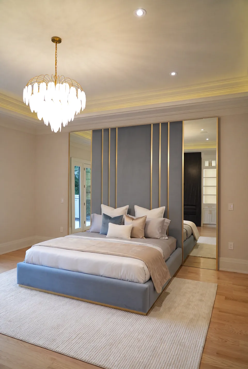 Angled full view of the slate-blue upholstered bed and mirrored headboard wall.