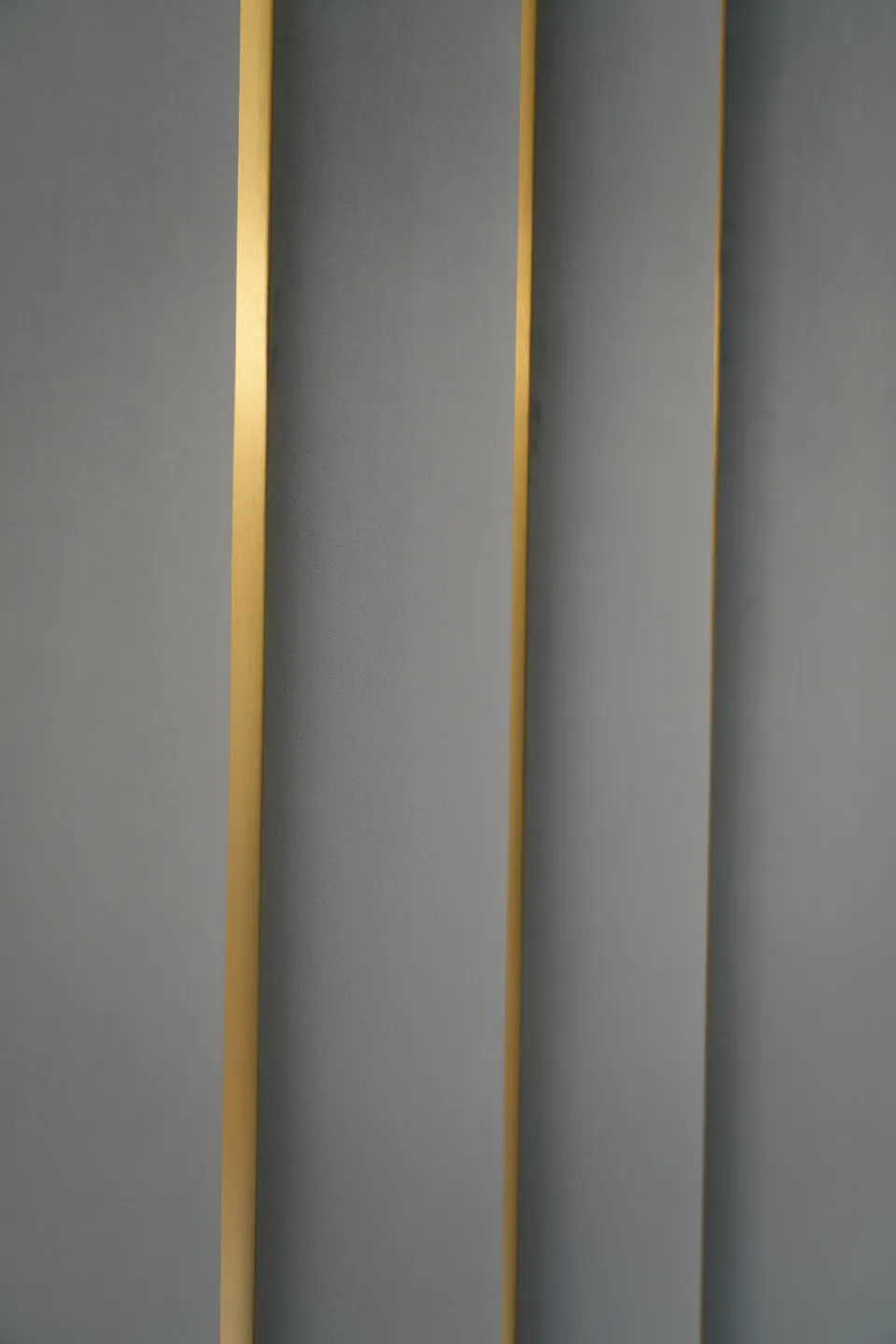 Detail of a gold strip between slate-blue upholstered wall panels.