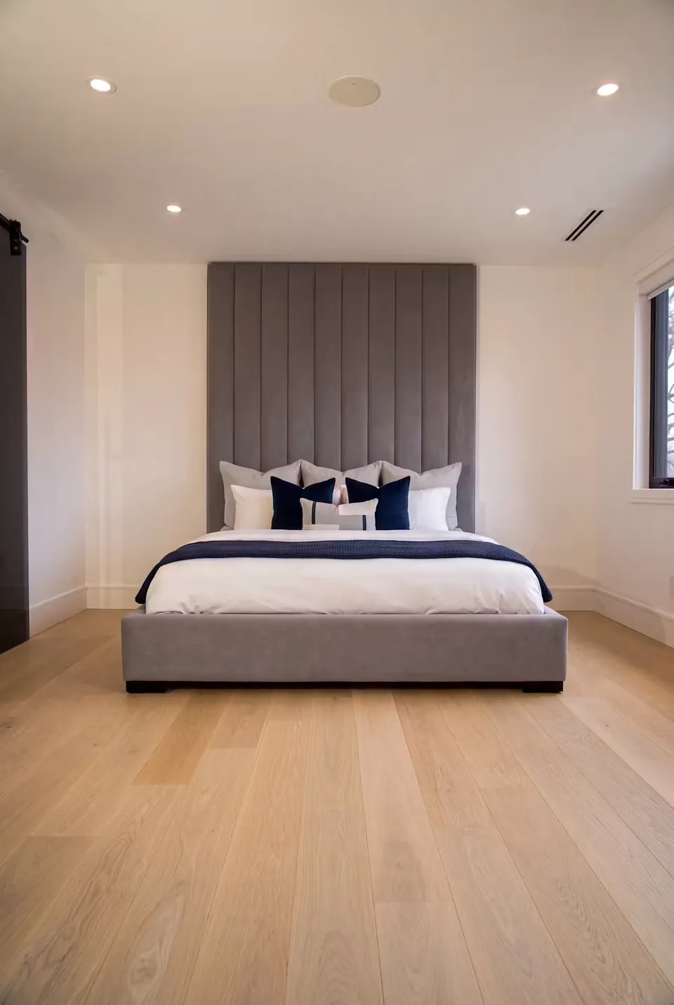 Front view of tall grey headboard channels above a plain upholstered bed frame