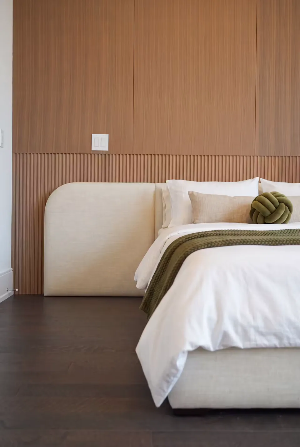 Detail of the softly rounded ivory headboard and white pillows