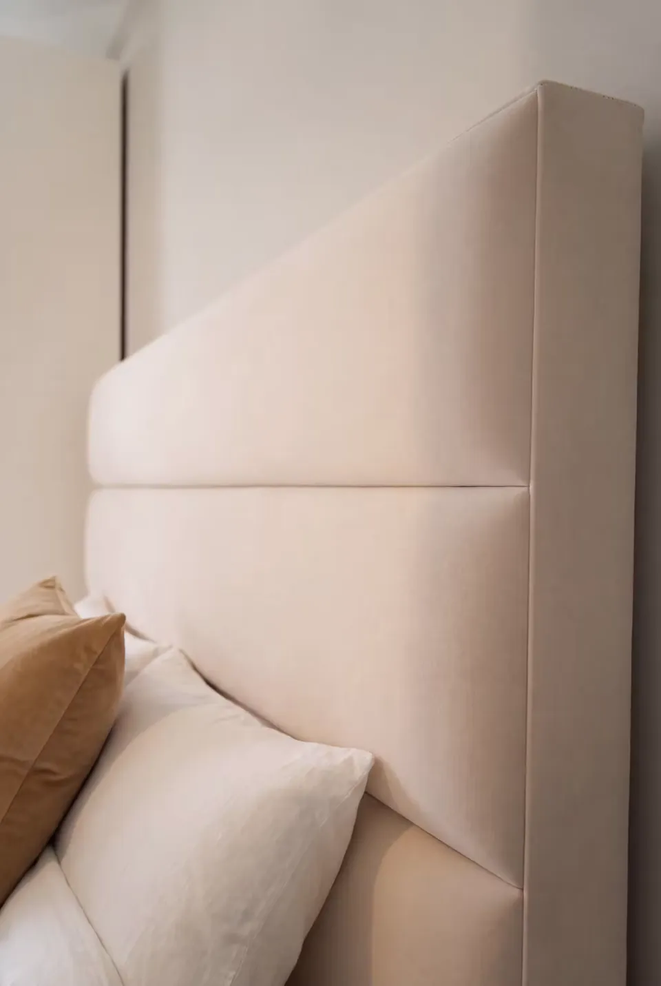 Close view of a horizontal seam and padded edge on the sand-coloured headboard.