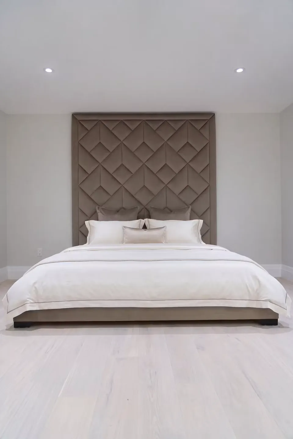 Full front view of a custom upholstered bed beneath a taupe geometric headboard