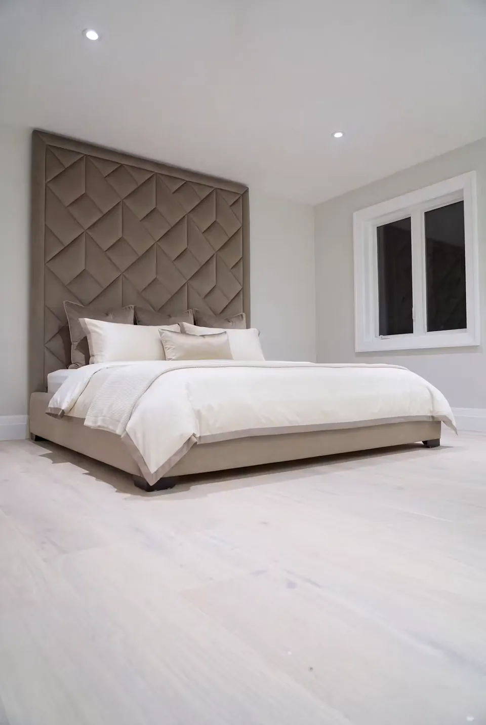 Angled view of the taupe bed and interlocking padded headboard