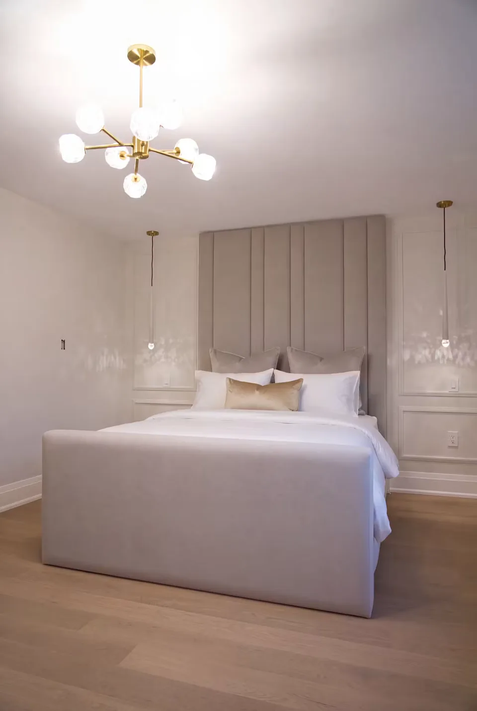 Full bedroom view showing the taupe bed beneath the ceiling light