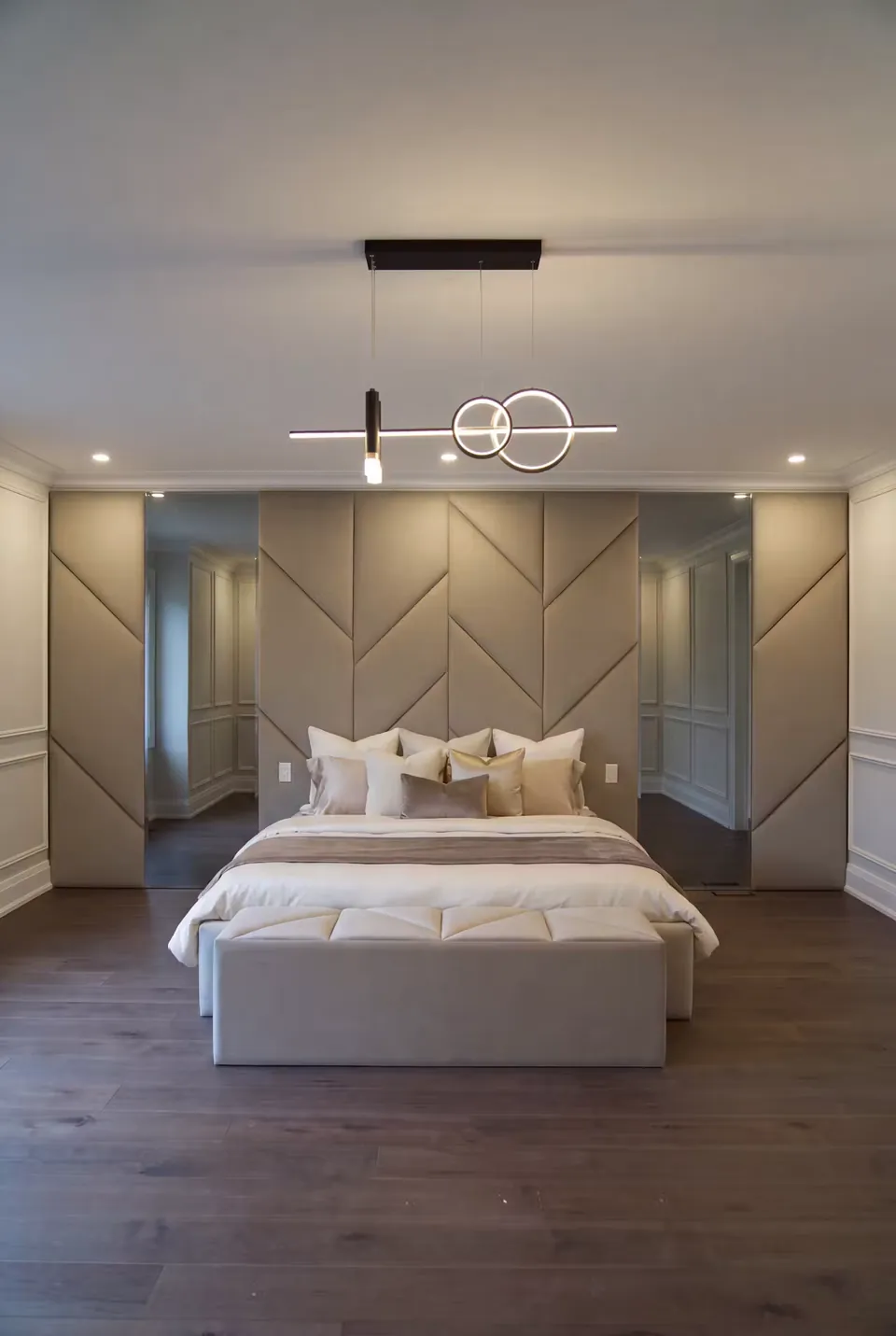 Wide front view of the taupe bed and angular upholstered wall.
