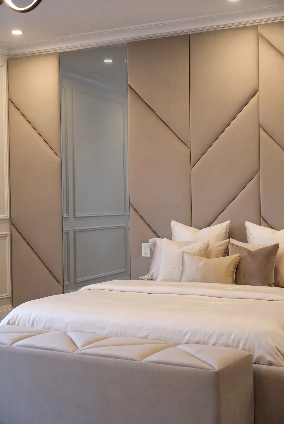 Detail of the taupe chevron headboard beside a tall mirror.