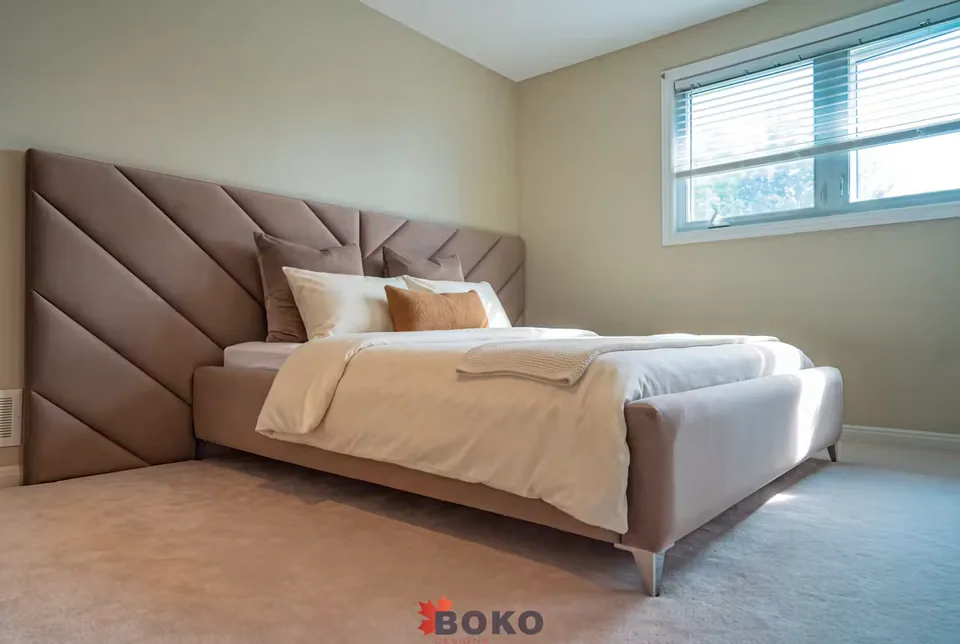 Wide angled view of the taupe bed beneath the extended diagonal headboard
