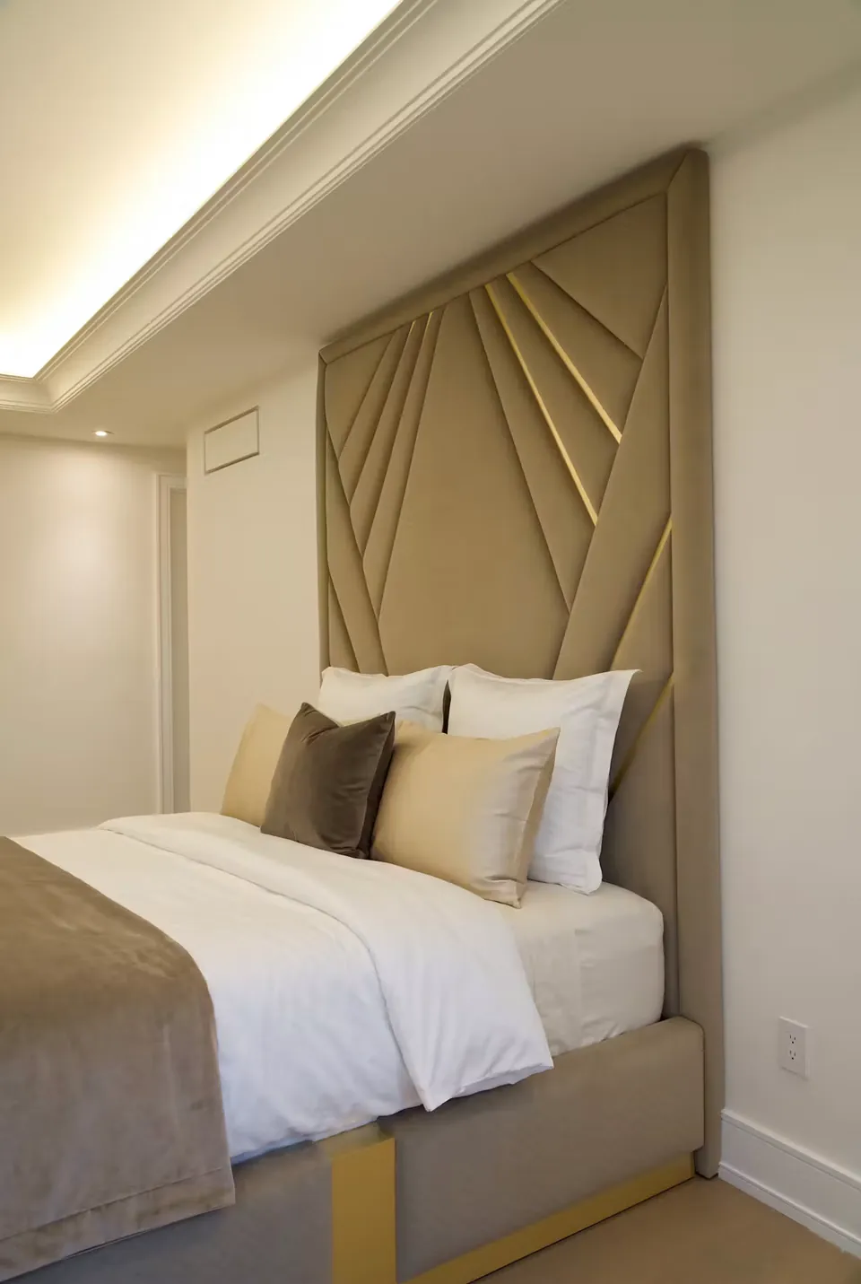 Angled view of the taupe geometric headboard and gold-edged upholstered frame.
