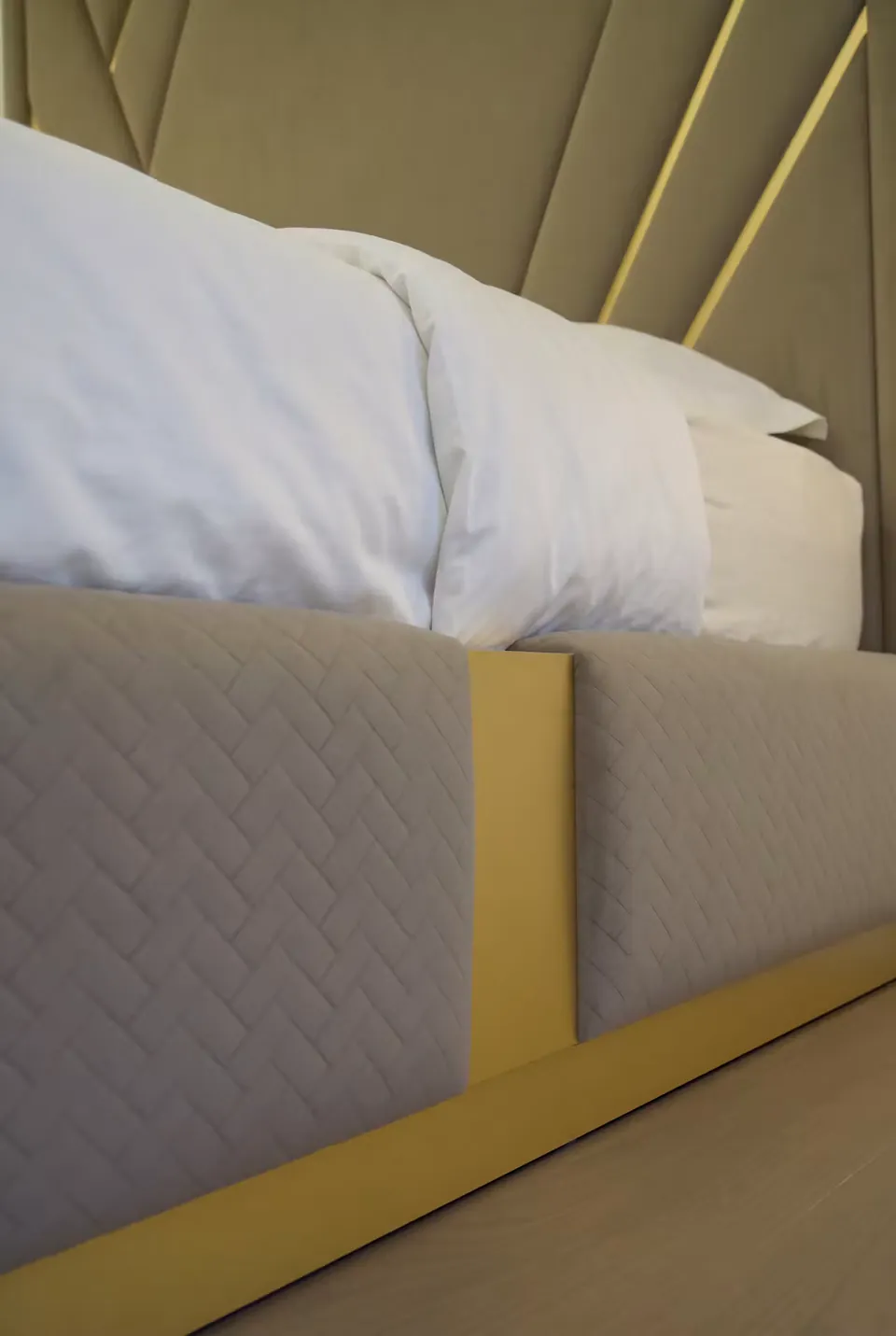 Close view of diamond-textured bed frame upholstery with a gold-toned border.