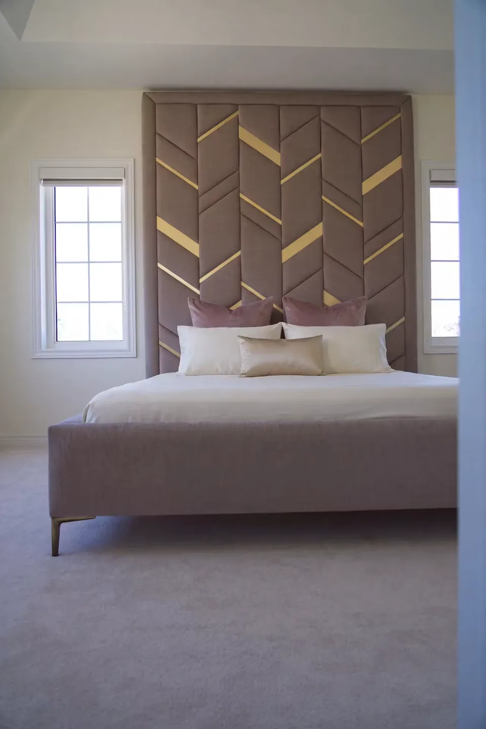 Full front view of the taupe upholstered bed beneath the geometric headboard
