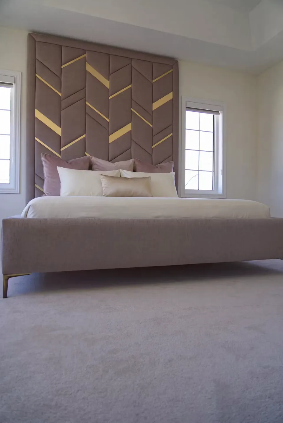Low angled view of the taupe bed and gold-divided chevron headboard
