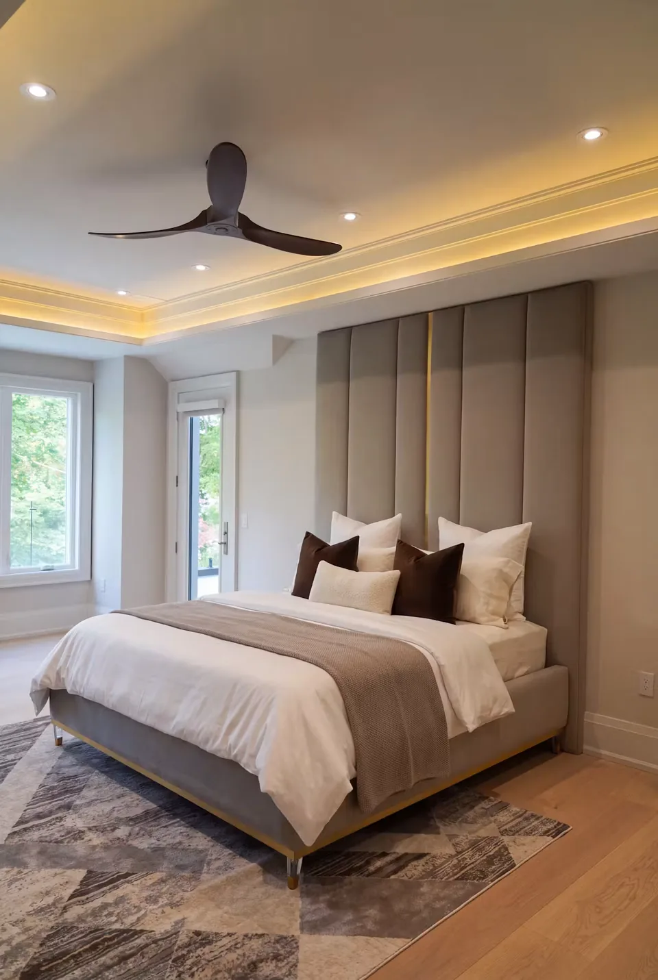 Taupe upholstered bed with tall vertical headboard panels and gold-toned base trim