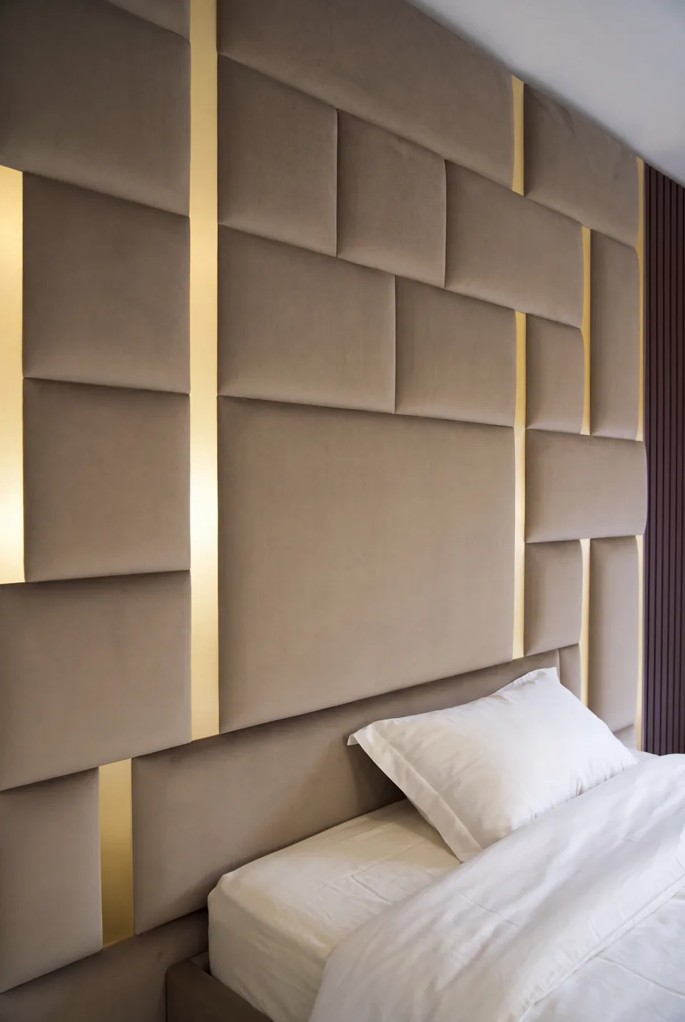 Close view of staggered taupe upholstery, slender gold divisions and the padded headboard.