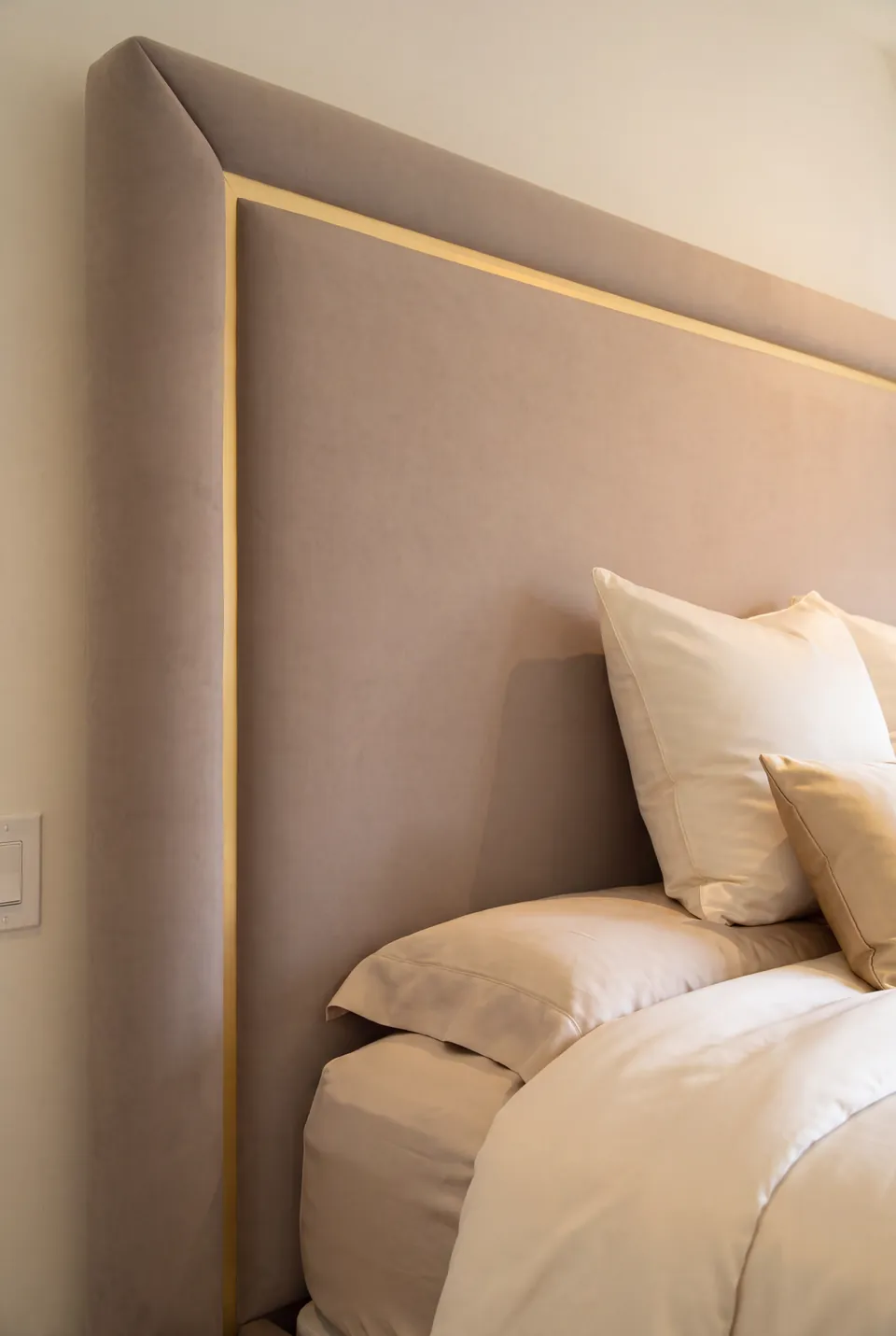 Detail of the gold headboard outline and padded taupe corner.