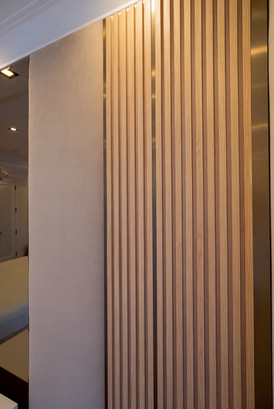 Close view of warm vertical slats next to a padded taupe wall panel.