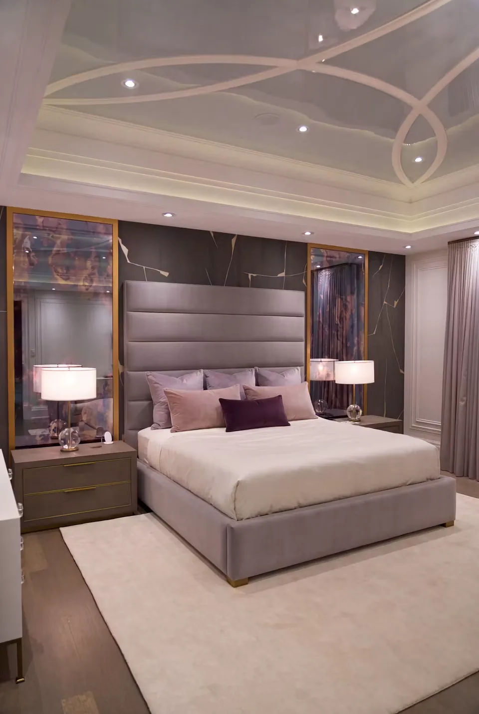 Wide angled view of the taupe upholstered bed and surrounding decorative wall
