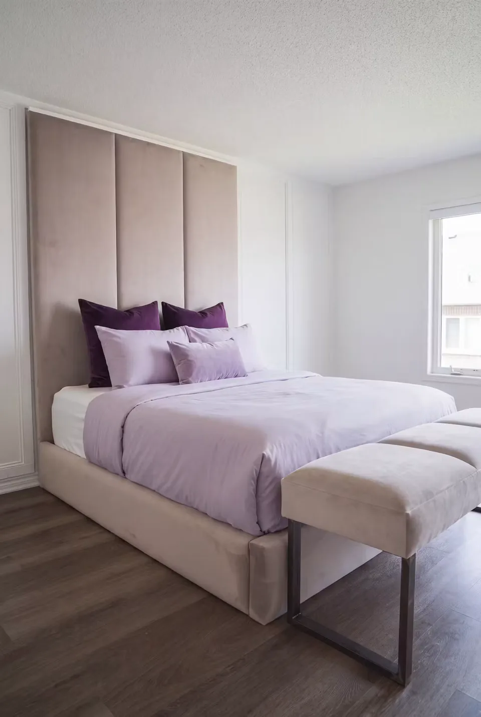 Wide view of the upholstered bed and bench beside the window