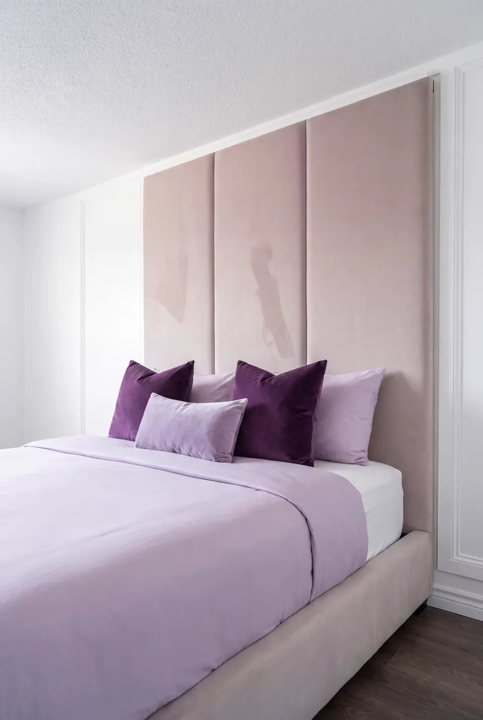Close view of the broad taupe headboard panels and pillows