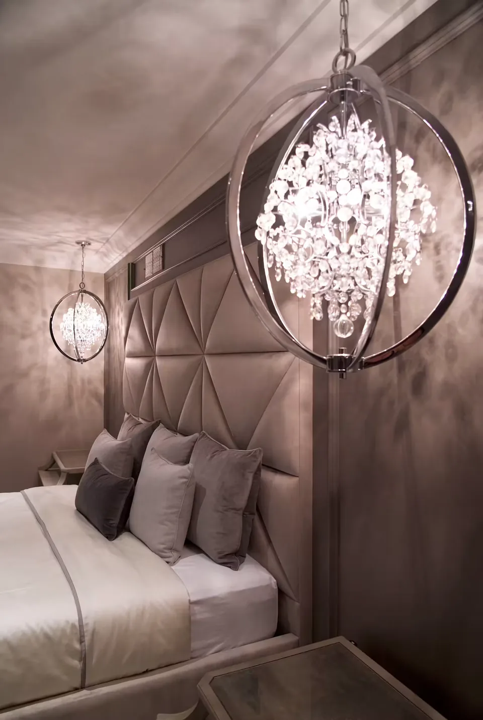 Detail of the padded headboard beside a hanging crystal light