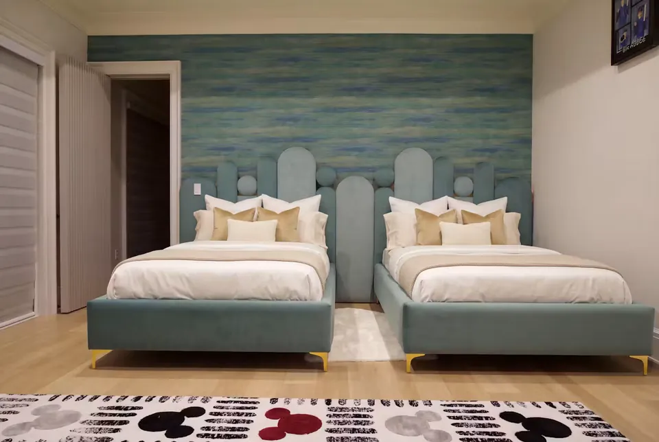 Full front view of two teal upholstered beds beneath rounded teal wall panels and circles.