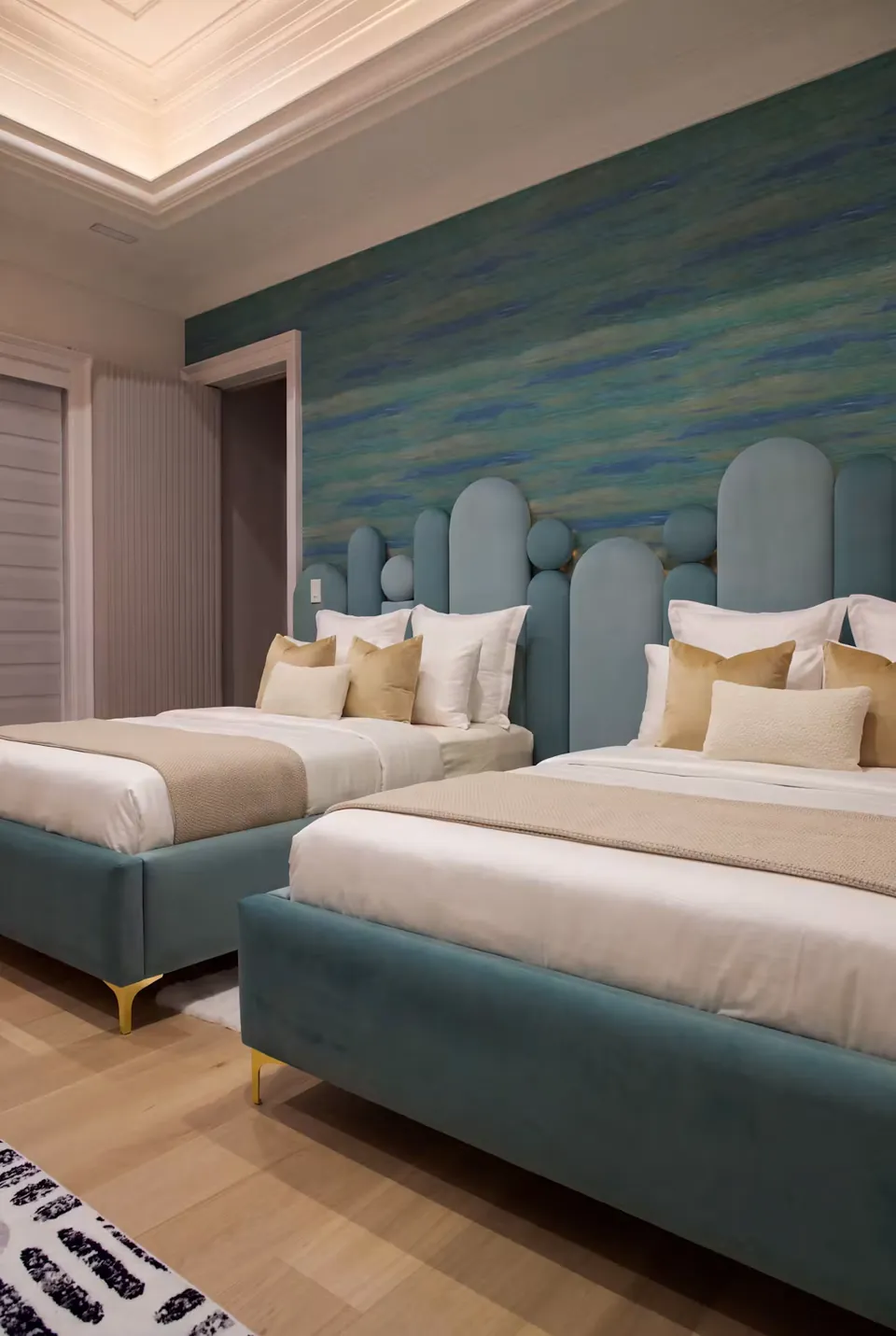 Angled view of the paired teal beds against a blue-green wall.