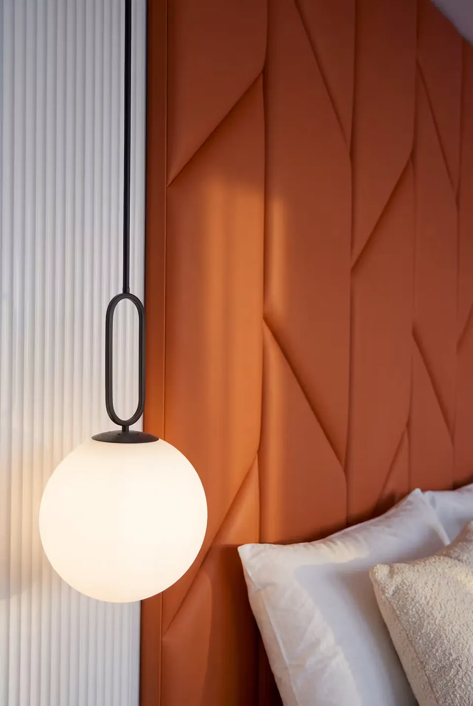 Detail of a globe pendant beside the terracotta geometric upholstery.