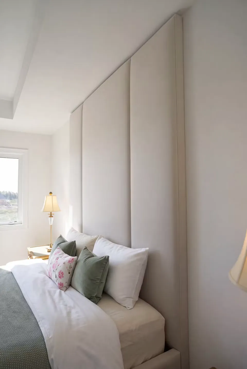 Side detail of broad grey headboard panels and green pillows.