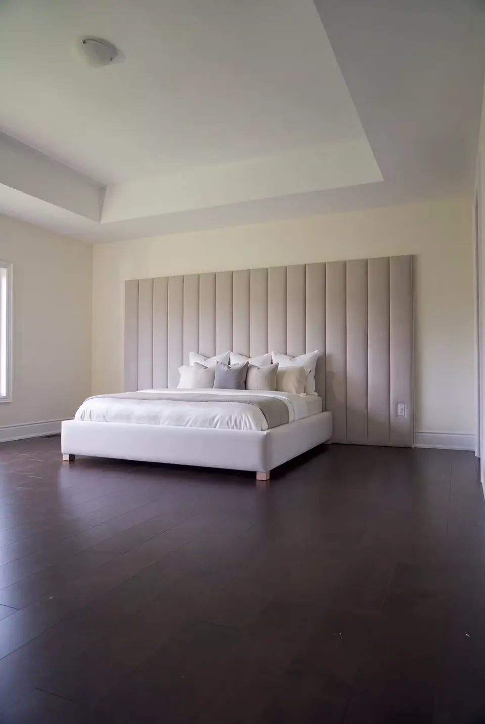 Full wide view of a white upholstered bed beneath a broad vertical channel wall.