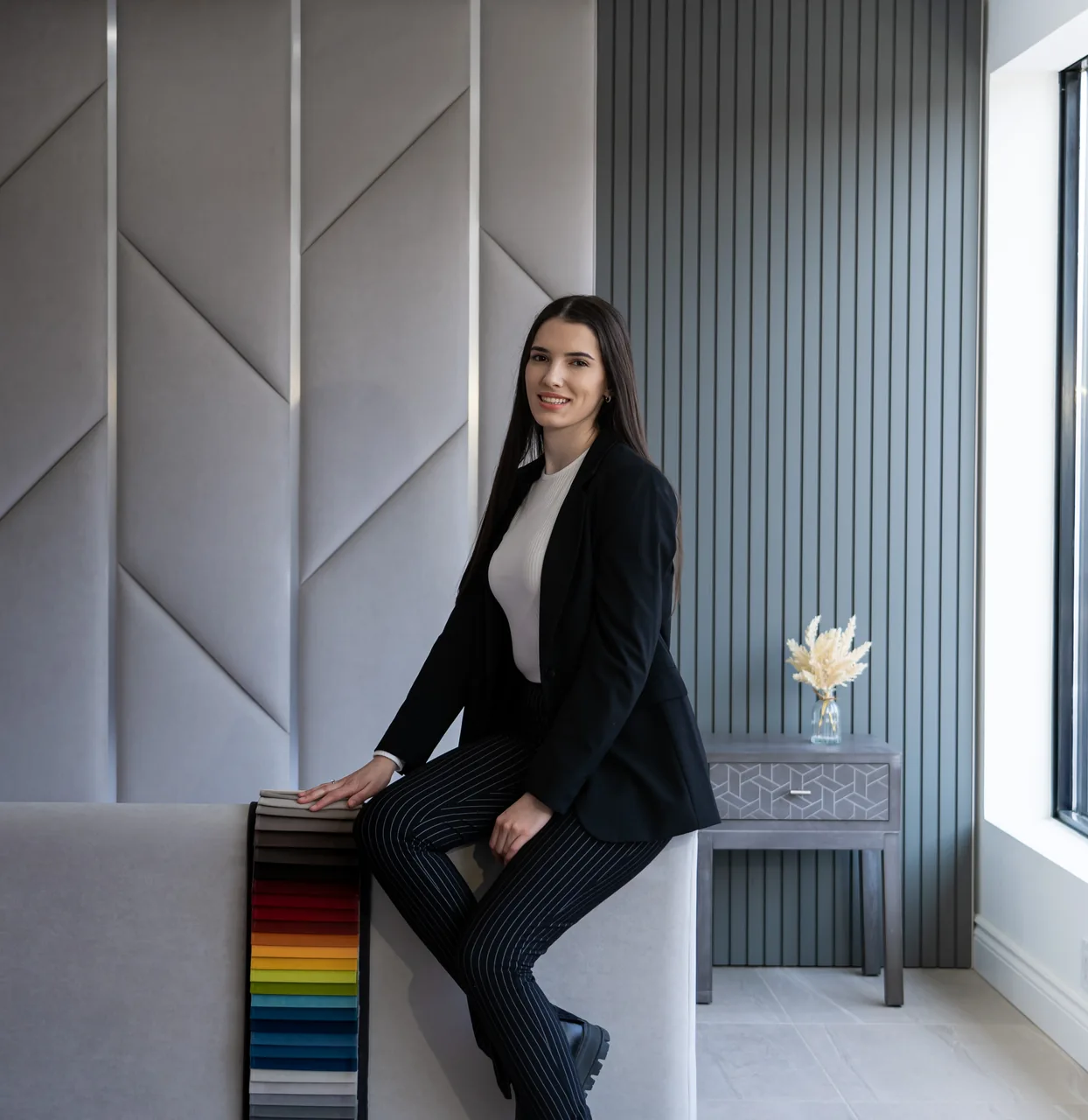 Danijela Brkovic seated beside fabric samples and upholstered panels in the BOKO showroom